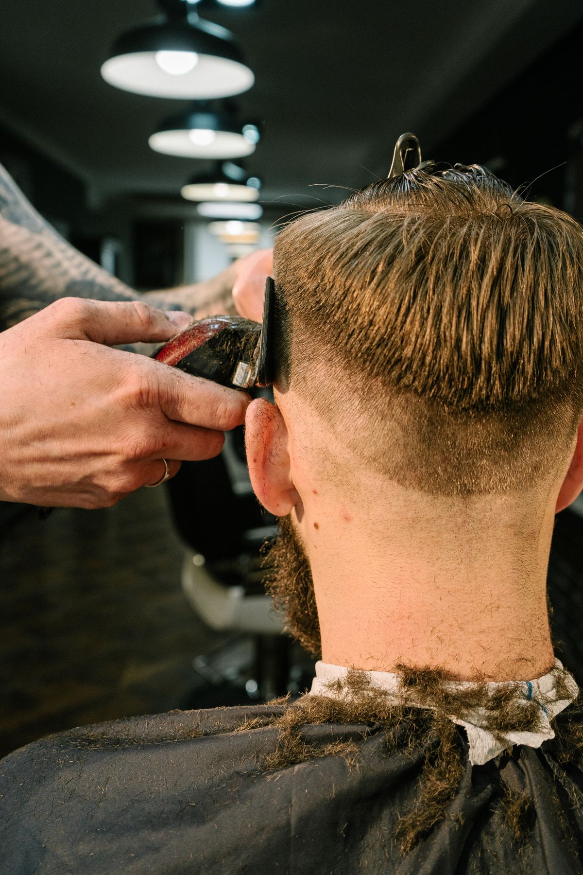 Coiffeur réalisant une coupe masculine à la tondeuse — photo d’inspiration